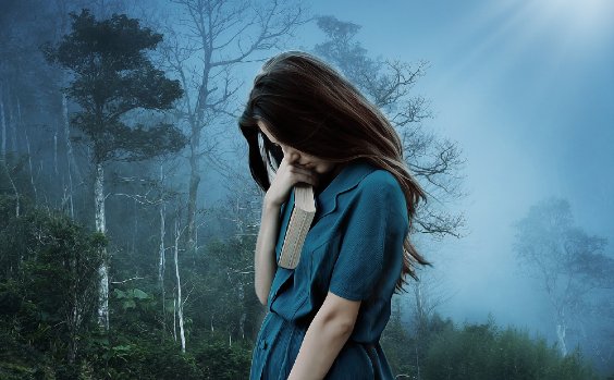 Traurige Frau mit Buch im Wald